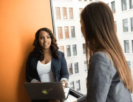 Two young women having a conversation at the office Two young women having a conversation at the office