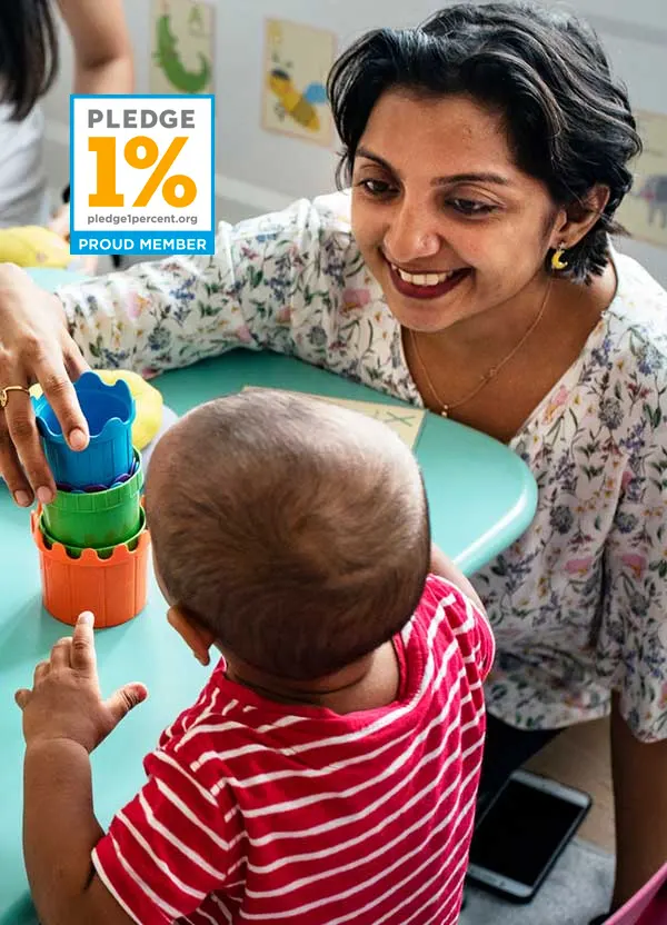 Female volunteer and young child playing with block toys