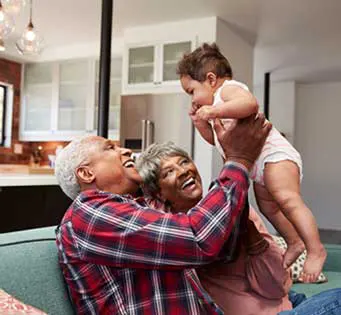 African-American grandmother and grandfather holding their grandchild in the air
