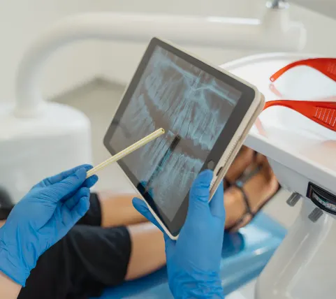 Dentist showing patient X-ray of teeth on a digital tablet