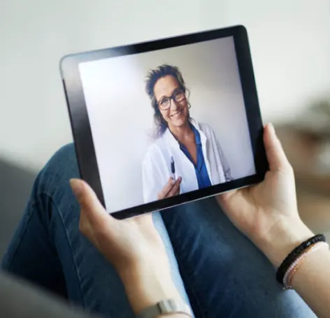 Woman holding tablet while having a video call with a female doctor