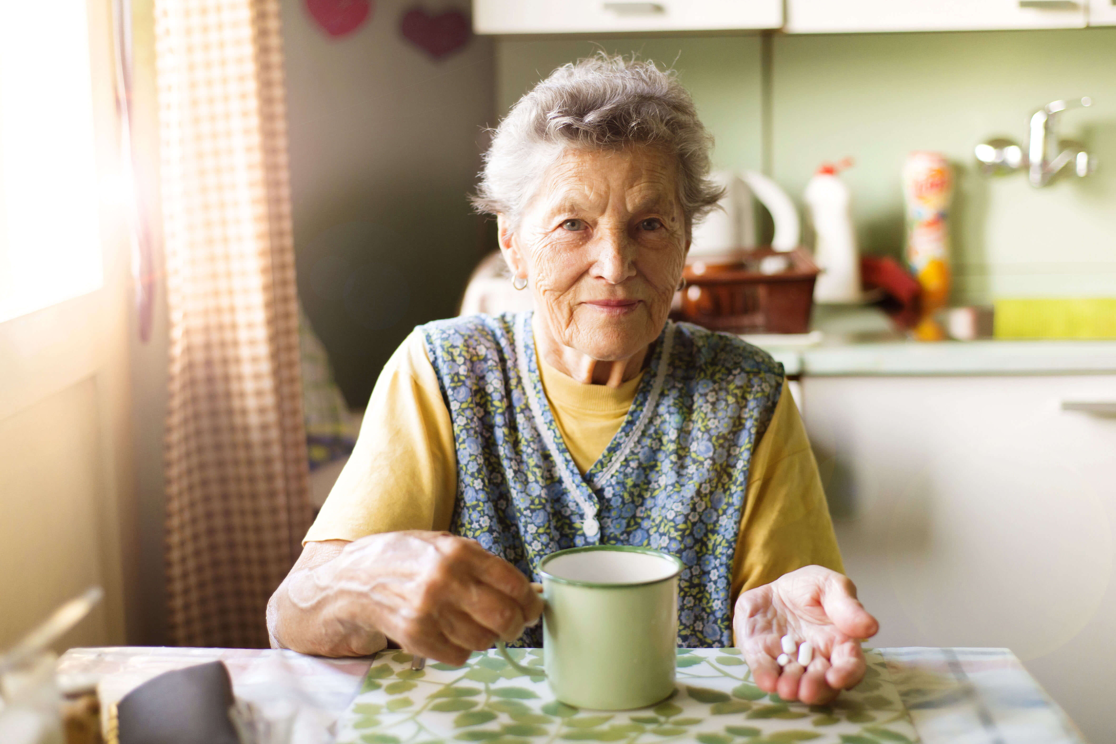 Senior woman holding prescription medications with cup of water